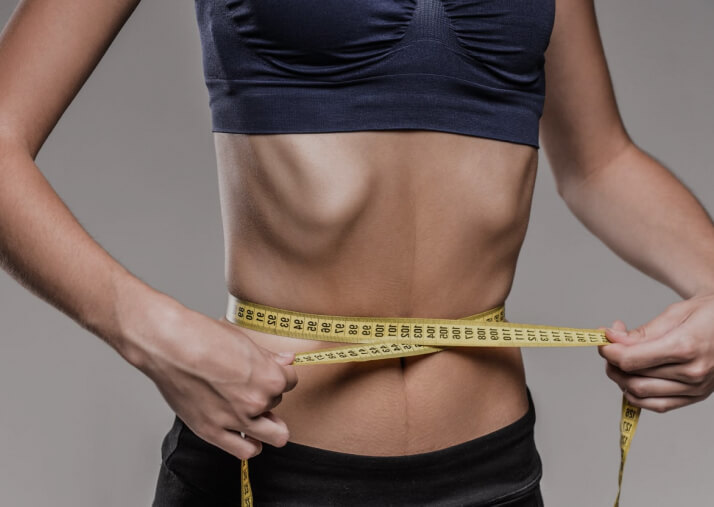 девушка измеряет талию